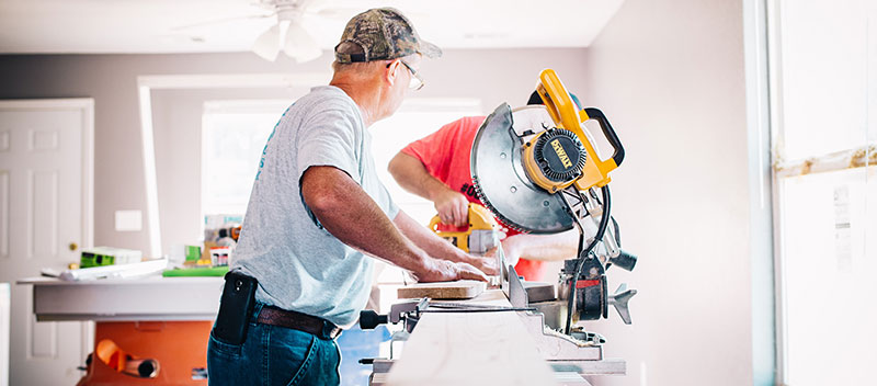 Workers cutting wood for home repair.