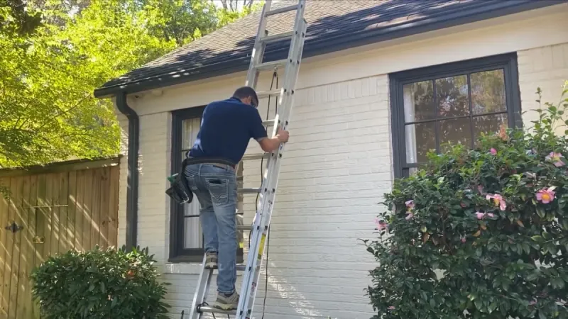 CrewPros tech on ladder for roof inspection.