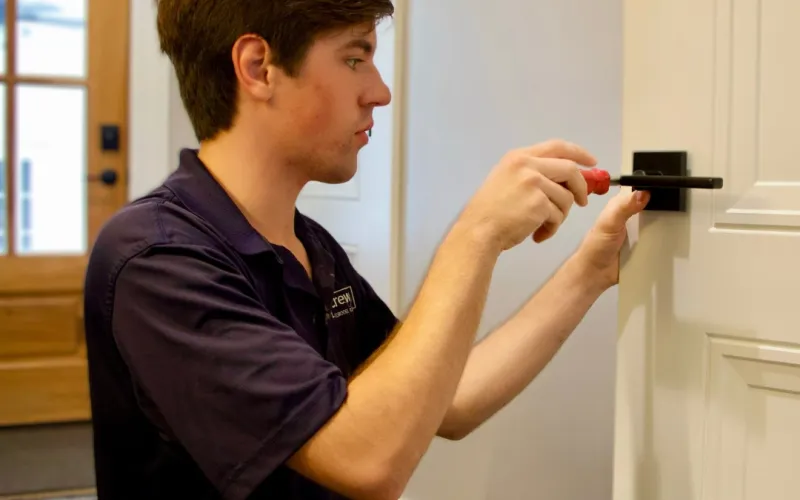 CrewPros employee changing a door handle.